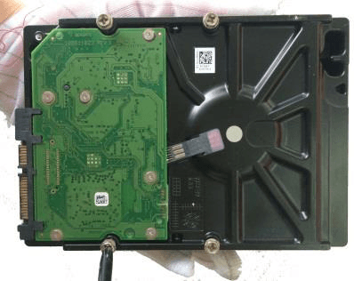 Hand holding a hard disk drive with screws fitted but not fastened