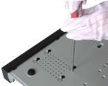 Underside of the chassis with a screwdriver fixing the HDD mounting screws