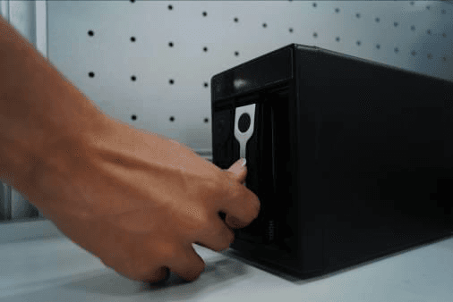 Hand pulling the HDD knob up at the front of the vertical chassis