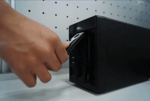 Hand pushing the HDD knob back down after inserting the HDD into the vertical chassis